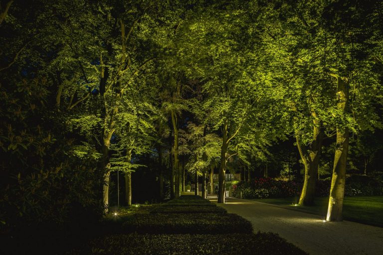 De balans tussen functionaliteit en sfeer is op deze foto goed te zien. De bomen zijn fraai en subtiele wijze verlicht en tegelijkertijd is het pad voldoende verlicht. In de achtergrond zie je de villa die zo verlicht is dat er een totale lichtbeleving ontstaat.